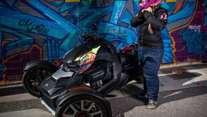 Rider adjusting her helmet next to Can-Am Ryker 900 Rally Edition