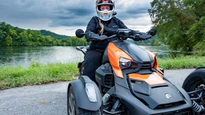 Rider on Can-Am Ryker 900 Rally Edition with lake behind her.
