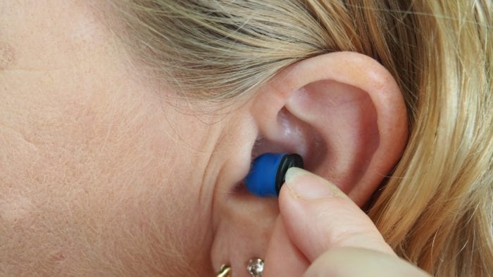 A woman inserting an earplug