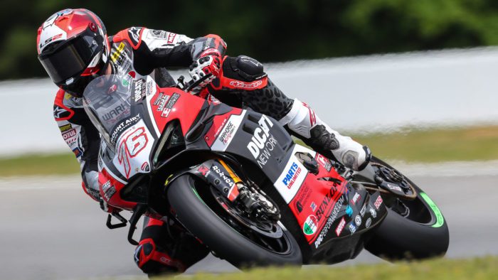 A front view of Loris Baz at the MotoAmerica Superbike Championship, leaning into a turn.