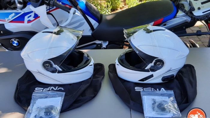 A view of two Outrush R Modular Helmets, in front of a BMW Motorcycle