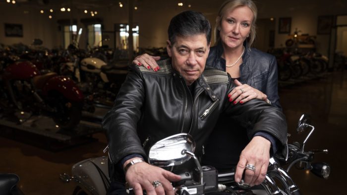 Robert Haas and partner as he sits on one of the motorcycles in his (Haas) Moto Museum