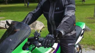 Man wearing Richa Airstorm WP Jacket while sitting on green Kawasaki motorcycle