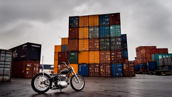 Shipping containers behind a beautiful motorcycle, symbolic of the shipping container inflation rates present in today's post