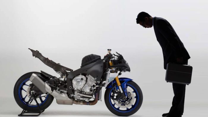 A view of a man bowing to a Yamaha motorcycle that's been stripped
