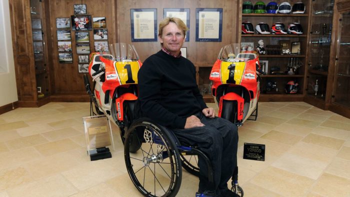 Wayne Rainey in his wheelchair with his championship winning bikes behind him